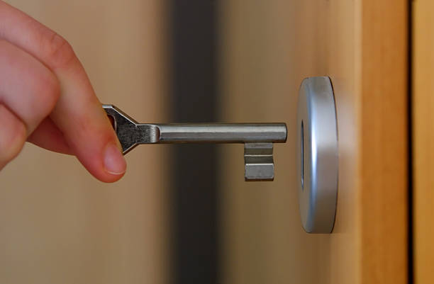 Close-up of fingers inserting a key into a door lock Hand holding key (with key hole) keyhole photos stock pictures, royalty-free photos & images
