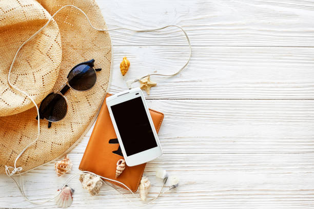 istock summer travel vacation concept flat lay, space for text.  passport plane hat  phone with empty screen and sunglasses and shells on white wooden background. hello summer. wanderlust 961902856