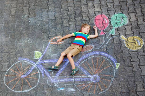 little kid boy having fun with bicycle chalks picture on ground - bicycle playing cards imagens e fotografias de stock