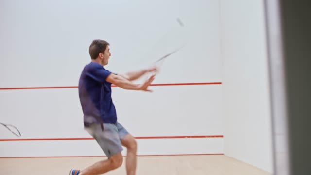 Two male friends playing squash