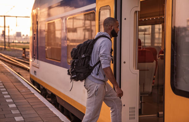 jonge mannelijke student van de niet-blanke wachten op een trein op een europese station op een mooie avond - trein nederland stockfoto's en -beelden