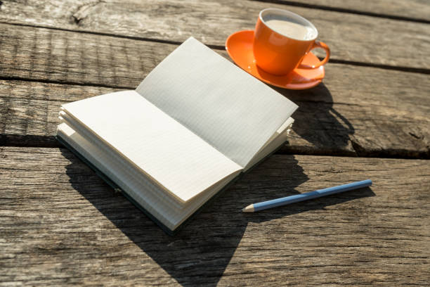 istock Blank white book with pencil and coffee cup over old weathered wooden table 961914210