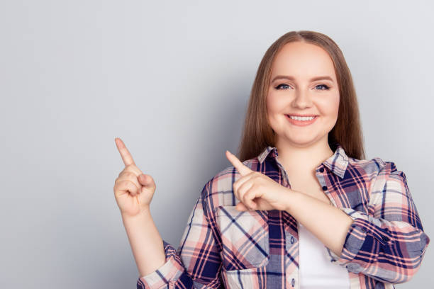 portret z kopią przestrzeni blondynki modny atrakcyjny wesoły model pokazujący puste miejsce z dwoma palcem wstecznym patrzącym na kamerę odizolowaną na szarym tle - chubby cheeks zdjęcia i obrazy z banku zdjęć