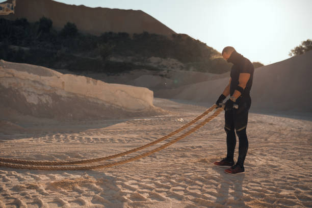 Strong man exercising with ropes in the quarry on a sunny day