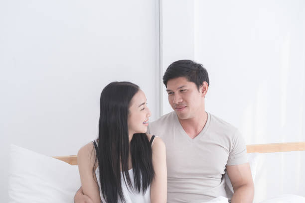 Happy Asian couple on bed with bright morning light Happy Asian couple on bed with bright morning light asian couple arguinasian couple intimateg stock pictures, royalty-free photos & images