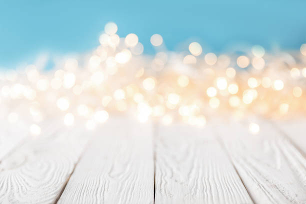 istock bright blurred lights on white wooden surface, christmas texture 961935544