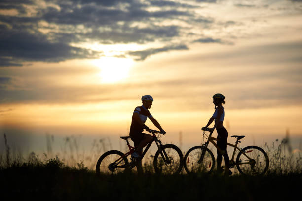istock Two cyclists posing with bikes against amazing sky background. 961944904