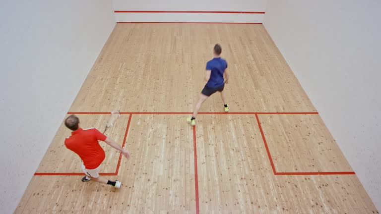 Male squash coach and his male student playing squash