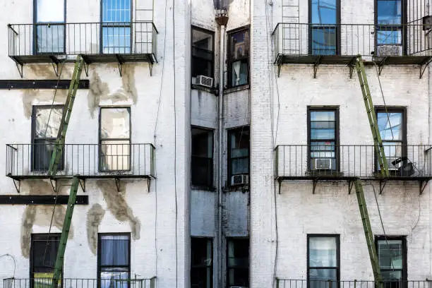 Old apartment condo building exterior architecture in Chelsea, NYC, Manhattan, New York City with fire escapes, windows, green ladders