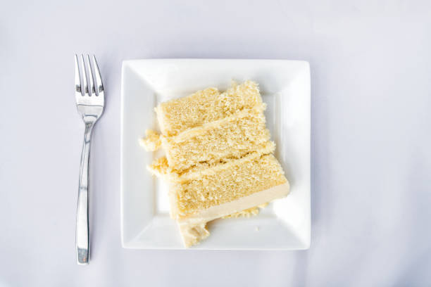 istock Flat top table setting lay view down closeup of restaurant or wedding reception white table tablecloth one plate with vanilla cream cake slice, fork 961956614