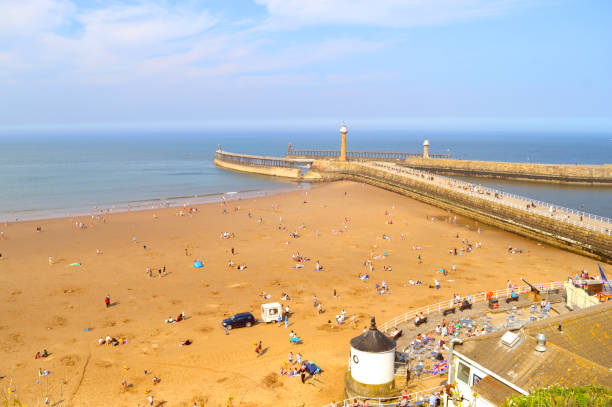 Tourists on Whitby beach West Cliff in North Yorkshire