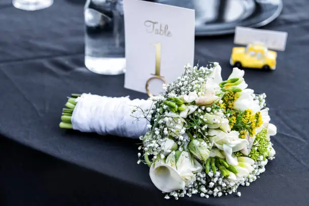 Wedding bouquet with many flowers, green yellow lily lying on black table background closeup floral arrangement on bride groom seating area