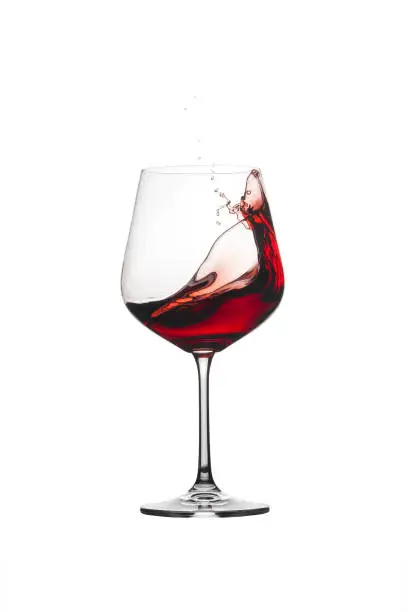 Red wine splashing out of a glass, isolated on white background. Wine with splash.