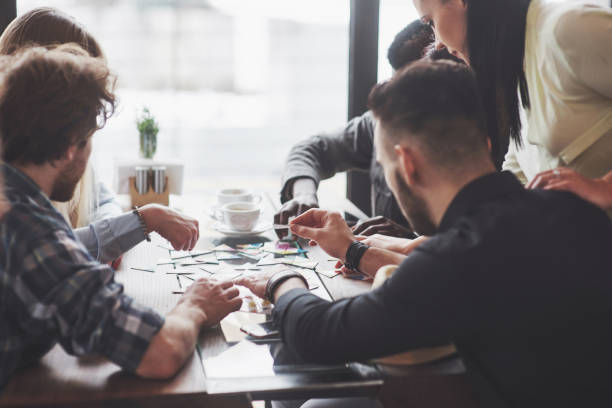 istock Group of creative friends sitting at wooden table. People having fun while playing board game 961961474