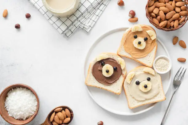 Photo of Animal face breakfast toasts with nut butter for kids on concrete background