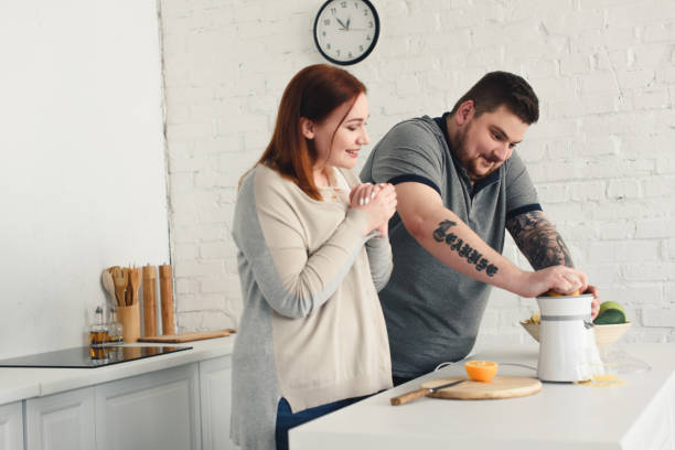 istock size plus girlfriend looking how boyfriend preparing orange juice at home 961966056