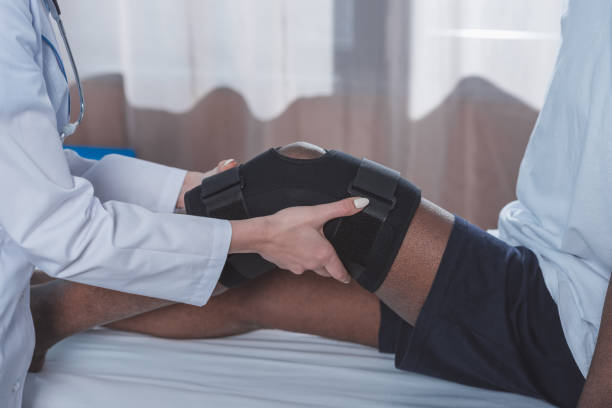 istock doctor putting on knee brace 961966166