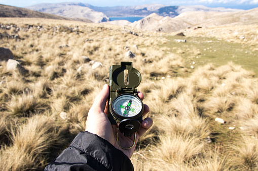 Hand holding compass against the horizon