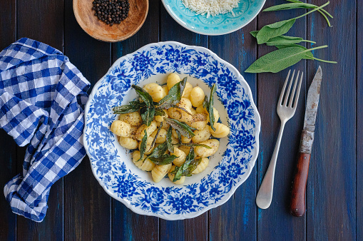 Gnocchi with sage and parmesan on wooden table