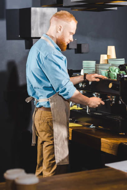istock young male barista in apron using coffee machine 961975818