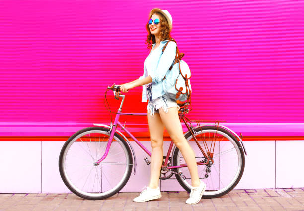 istock Cool girl with bicycle over colorful pink background 961999202