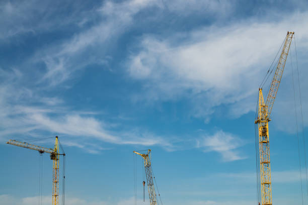 istock Big tower cranes against the blue sky. Background image of construction equipment close-up with copy space. Build of city. 962000600