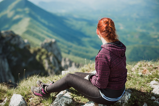 Young climer sitting on the edge of cliff, enjoying the view and fresh air