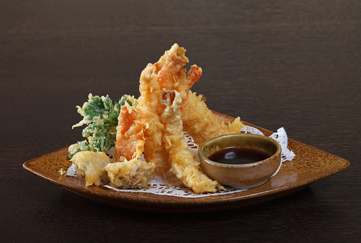 Tempura shrimps (deep fried shrimps) with soy sauce on wooden background.