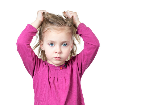 Little beautiful sad girl pulls her hair isolated on white background