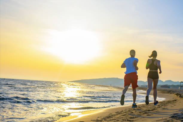 istock Man and women running on tropical beach at sunset 962012642