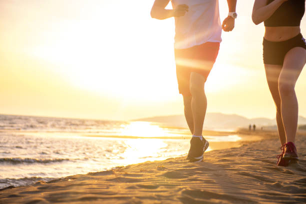 istock Man and women running on tropical beach at sunset 962021604