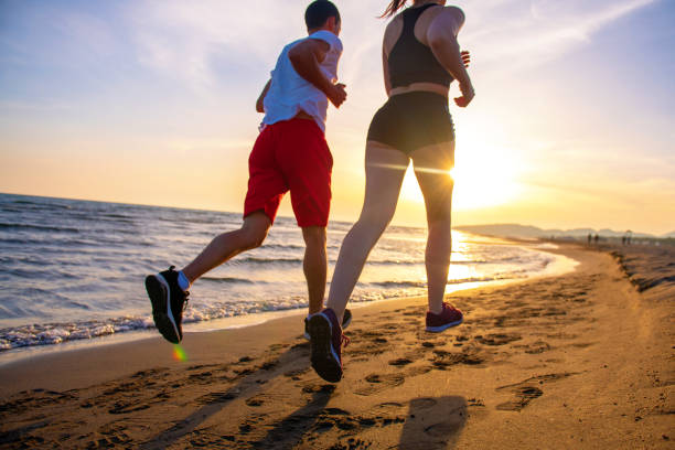 istock Man and women running on tropical beach at sunset 962027208