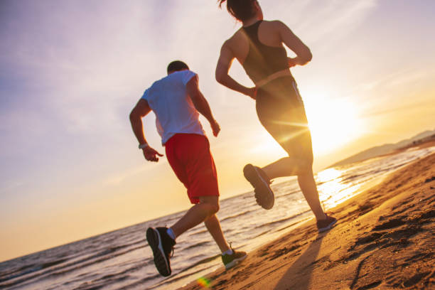 Man and women running on tropical beach at sunset