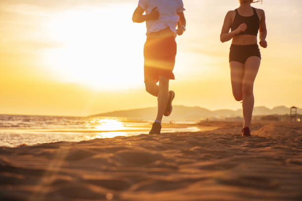 istock Man and women running on tropical beach at sunset 962028314