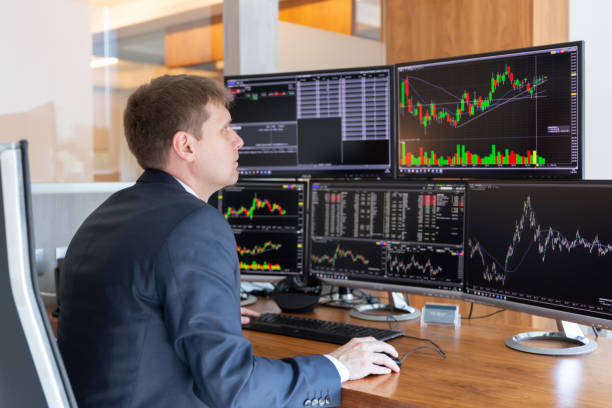 istock Stock trader looking at computer screens in trdading office. 962031032