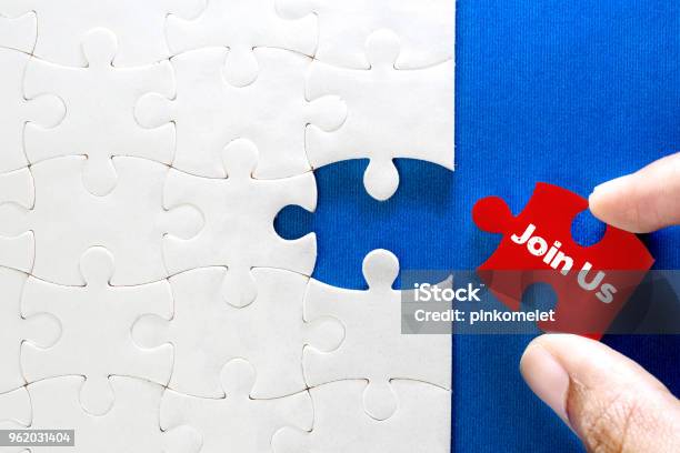 Close Up Piece Of White Jigsaw Puzzle With Join Us Text Concept Of A Business Challenge Success Completion With Teamwork Stock Photo - Download Image Now