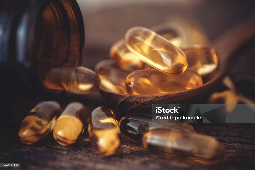 Cerca de la vitamina D y el suplemento de cápsulas de aceite Omega 3 pescado en placa de madera de buen cerebro, corazón y salud beneficios de comer - Foto de stock de Complemento vitamínico libre de derechos