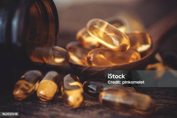 Close Up The Vitamin D And Omega 3 Fish Oil Capsules Supplement On Wooden Plate For Good Brain Heart And Health Eating Benefit Stock Photo - Download Image Now