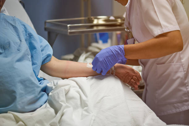 Nurse injecting catheter in hand Nurse injecting catheter in hand of patient close up catheter photos stock pictures, royalty-free photos & images