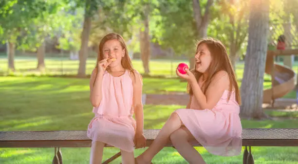 Twin sisters with apple and donut