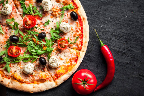 istock Margarita pizza with  mozzarella cheese, cherry tomatoes on black stone background,  copy space for your text 962042400