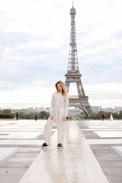 istock Stylish caucasian lady standing near Eiffel Tower in white overalls 962054862