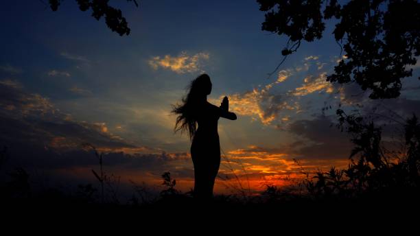 istock Dark female silhouette praying in evening sky background 962056188