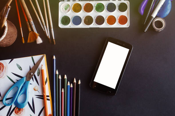 istock smartphone cell with empty white screen and colorful pencils paints brushes scissors  on chalkboard, space for text, flat lay, back to school concept 962064984