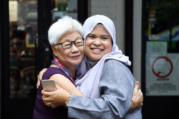 Elderly senior and young woman headscarf meet great hugging stock photo