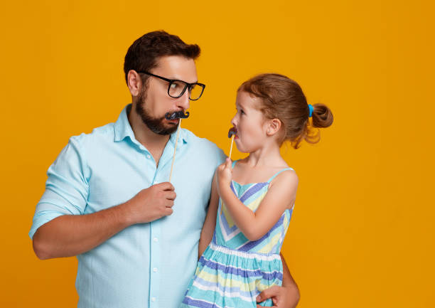 happy father's day! funny dad and daughter with mustache fooling around on yellow background happy father's day! funny dad and daughter with mustache fooling around on colored yellow background happy fathers day funny stock pictures, royalty-free photos & images