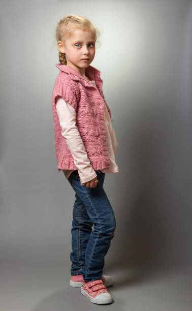 istock Little blonde with grey eyes shows off clothes on grey 962074774