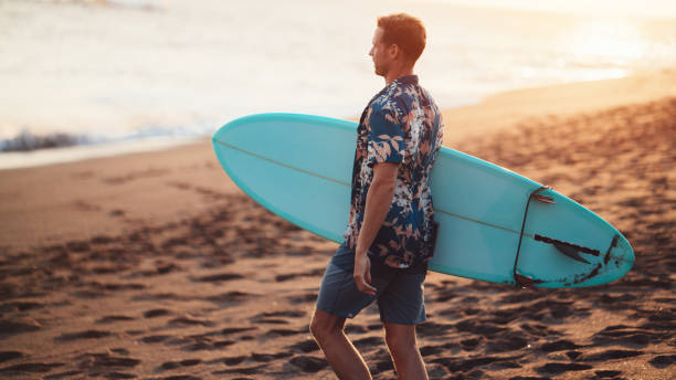istock Surfer with a surfboard on the beach 962077224