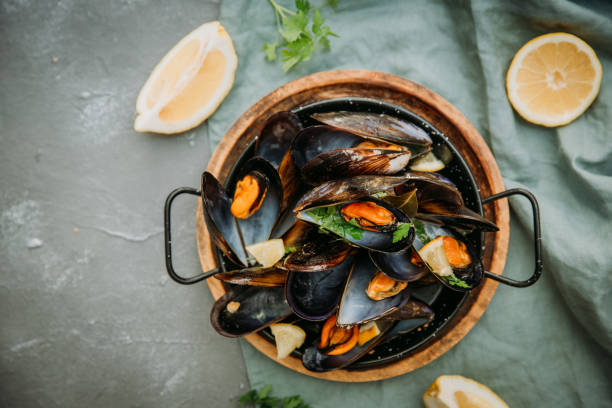 istock Traditional blue mussel in white wine on stone background, top vie, copy space 962078034