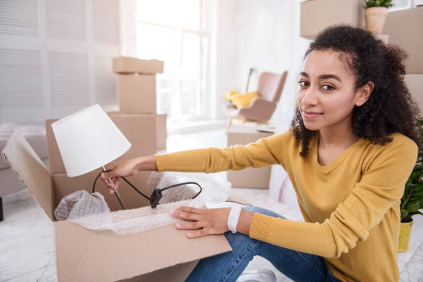 istock Pleasant cheerful girl taking out lamp while unpacking belongings 962088802
